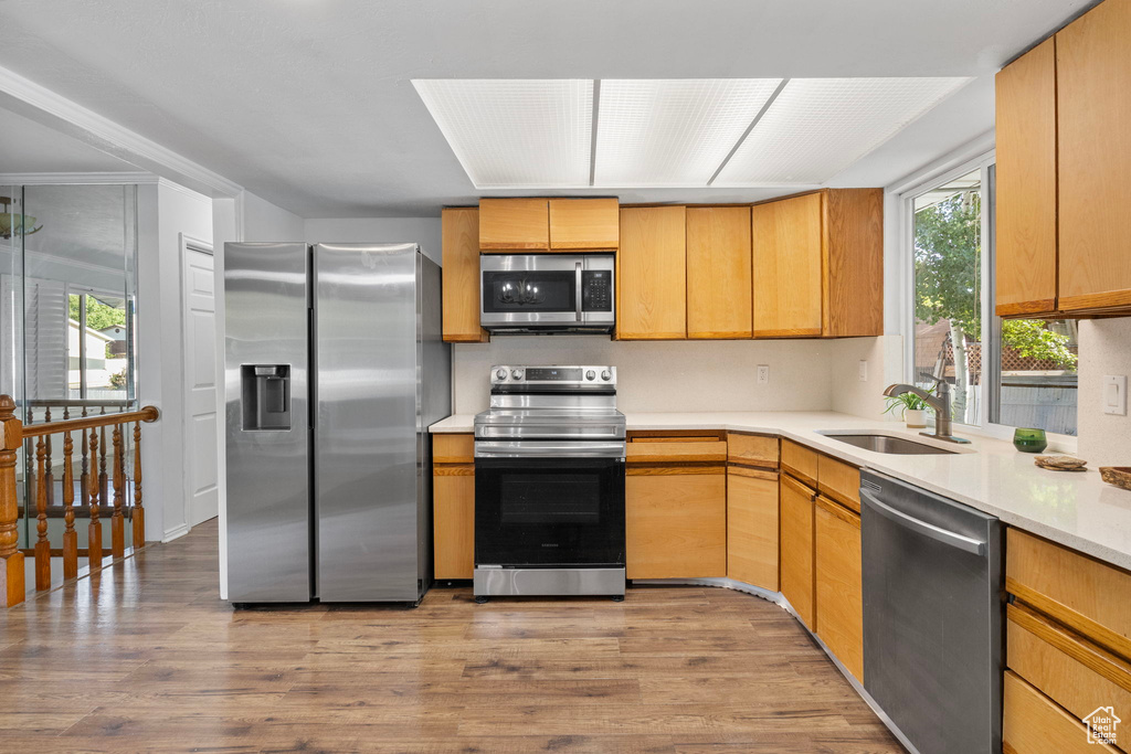Kitchen with stainless steel appliances, wood finished floors, and light countertops