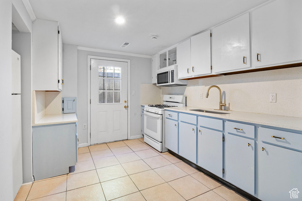 Kitchen with white appliances, blue cabinets, light tile patterned flooring, light countertops, and white cabinets