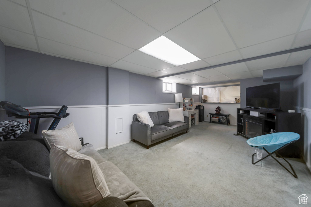 Living area with a drop ceiling, carpet, and a wainscoted wall