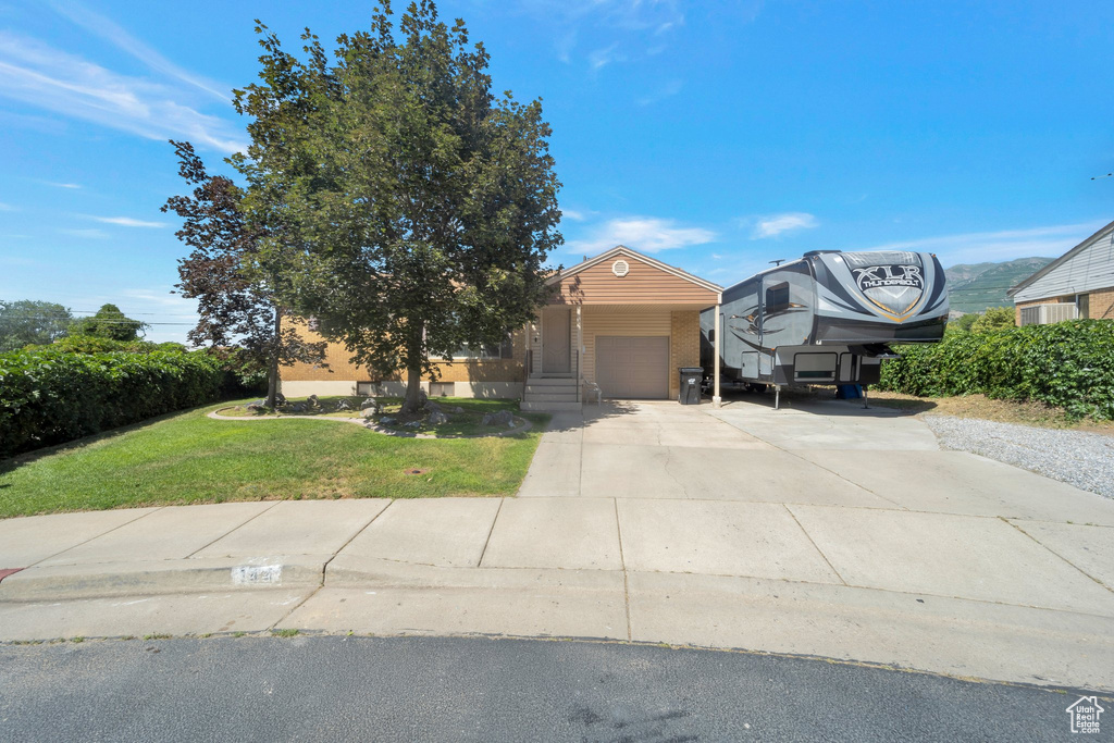 Obstructed view of property featuring a front yard, driveway, and an attached garage