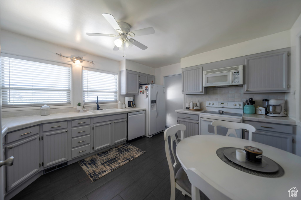 Kitchen with white appliances, gray cabinets, a ceiling fan, light countertops, and tasteful backsplash