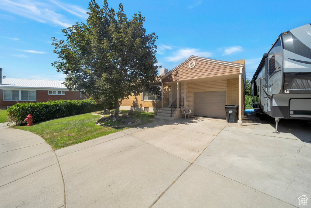Ranch-style house with an attached garage, concrete driveway, a front lawn, and brick siding