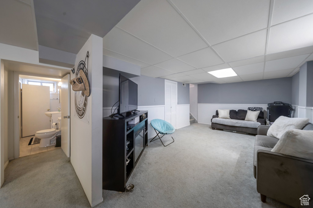Carpeted living area with a wainscoted wall and a paneled ceiling