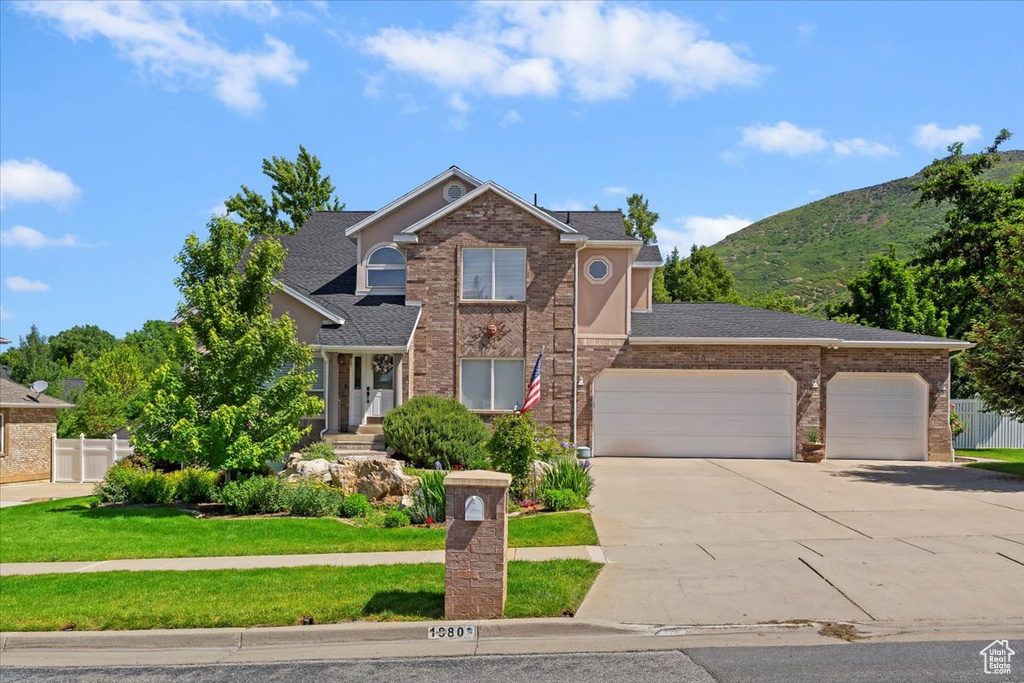 Traditional-style home featuring concrete driveway, an attached garage, brick siding, and a mountain view