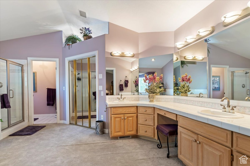 Full bathroom with vaulted ceiling, a stall shower, and double vanity