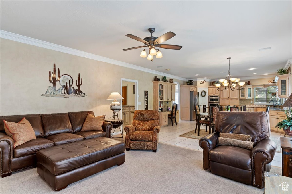 Living area with a chandelier, a ceiling fan, light tile patterned floors, ornamental molding, and light carpet