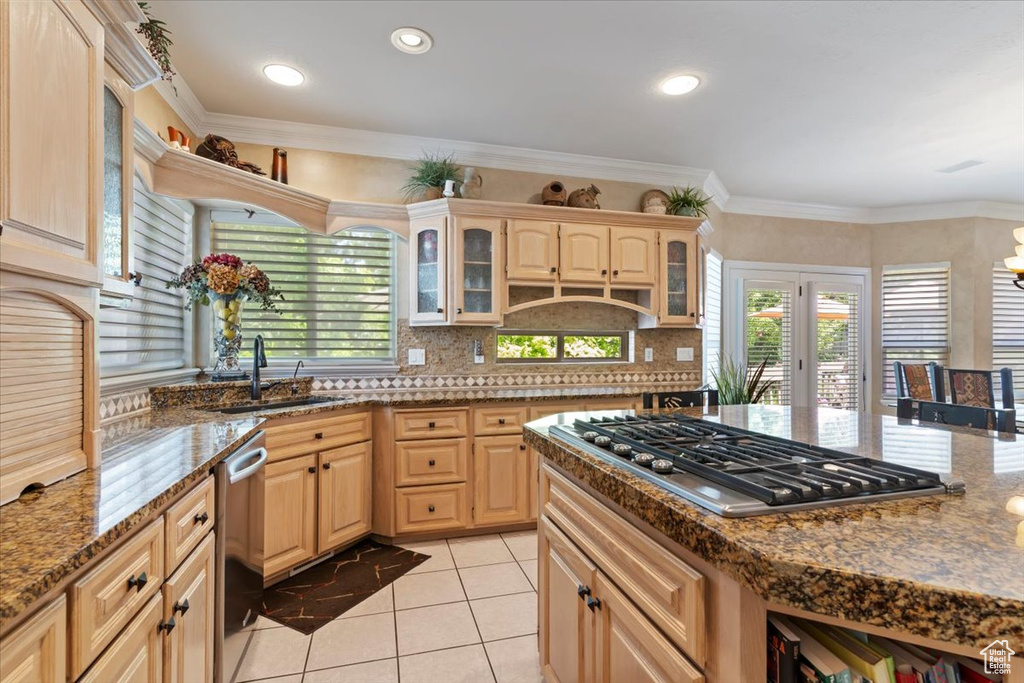 Kitchen with appliances with stainless steel finishes, decorative backsplash, light tile patterned flooring, glass insert cabinets, and light brown cabinetry