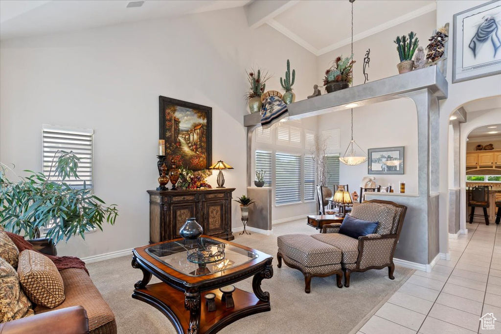 Living area with arched walkways, high vaulted ceiling, plenty of natural light, light tile patterned floors, and beamed ceiling