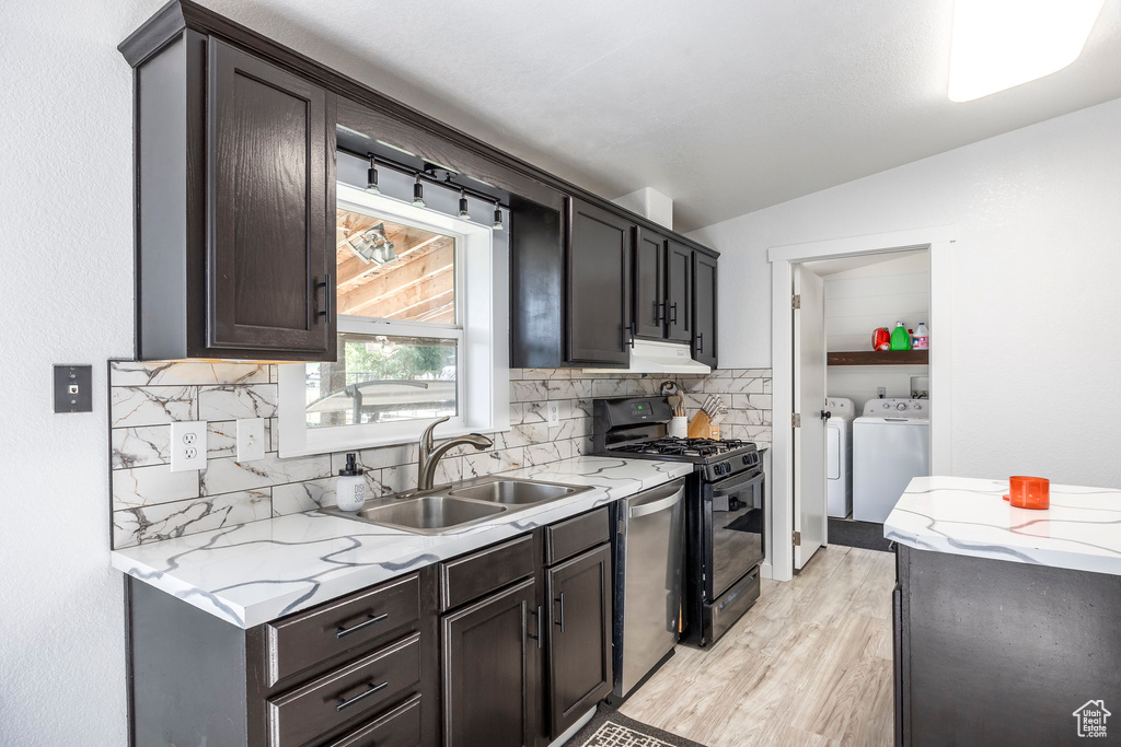 Kitchen with washing machine and clothes dryer, dishwasher, backsplash, gas stove, and light wood-type flooring