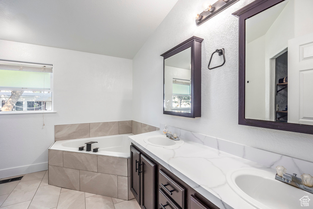 Bathroom featuring a garden tub, double vanity, and tile patterned floors