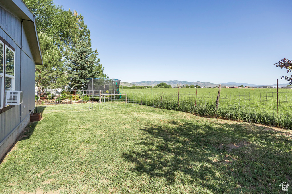View of yard featuring a trampoline, a rural view, a mountain view, and cooling unit