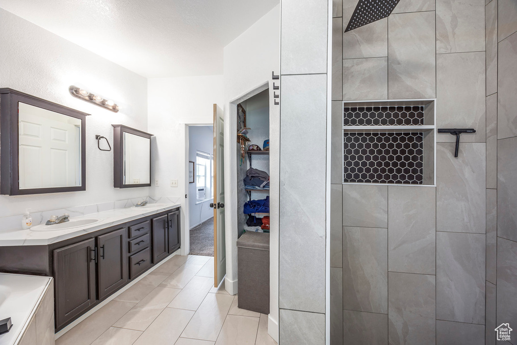 Full bath featuring double vanity, tiled shower, and a walk in closet