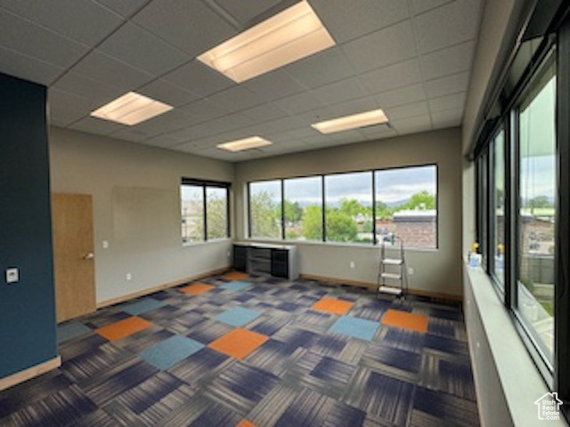 Carpeted empty room featuring baseboards and a paneled ceiling