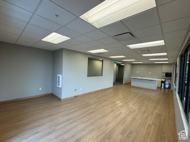 Unfurnished room with light wood-type flooring, a drop ceiling, and fire sprinkler in ceiling