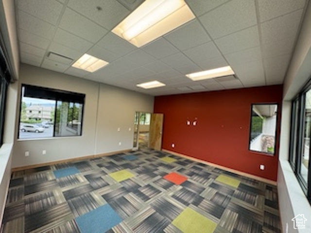 Carpeted spare room with a drop ceiling and baseboards