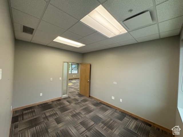 Unfurnished room featuring a drop ceiling and carpet floors