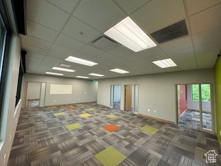 Carpeted empty room with a paneled ceiling and baseboards