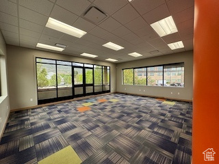 Empty room featuring carpet flooring and a paneled ceiling