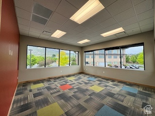 Carpeted empty room featuring a drop ceiling