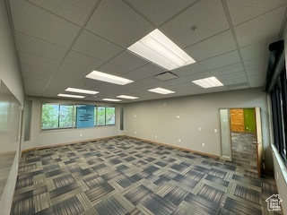 Carpeted spare room with baseboards and a paneled ceiling