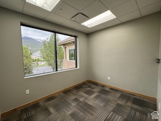 Unfurnished room with a paneled ceiling and carpet flooring