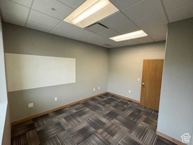 Unfurnished room featuring a paneled ceiling and dark carpet