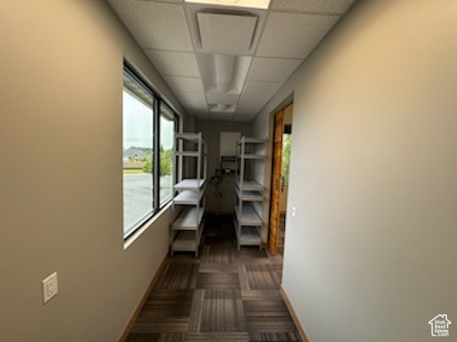 Hall with baseboards and a paneled ceiling