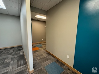 Corridor featuring carpet and a paneled ceiling