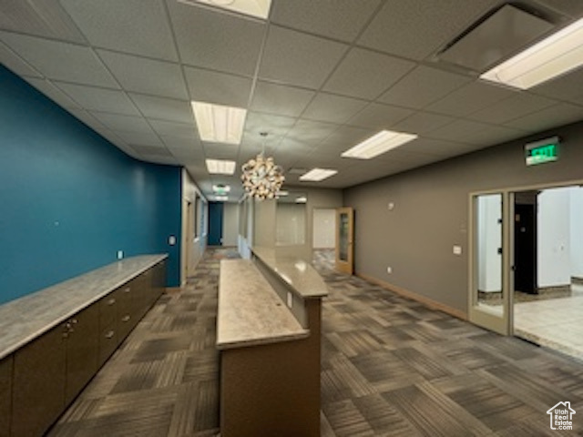 Kitchen with dark carpet, a chandelier, a drop ceiling, dark brown cabinetry, and light countertops