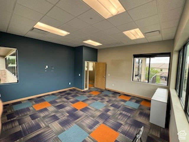 Carpeted spare room with a drop ceiling and baseboards