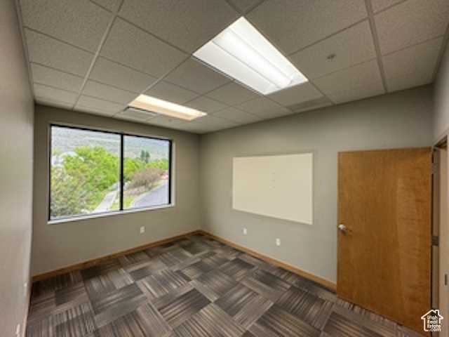 Unfurnished room featuring a drop ceiling and baseboards