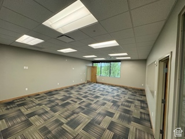 Carpeted empty room with baseboards and a paneled ceiling