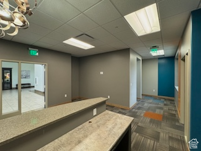 Interior space with a paneled ceiling, light countertops, and carpet flooring