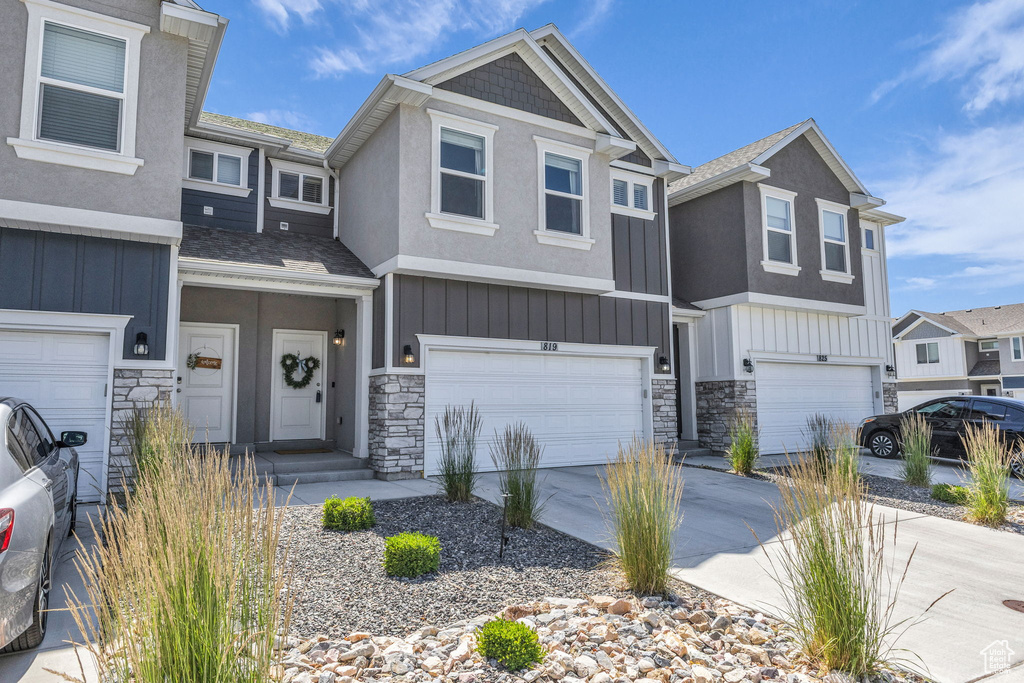 Multi unit property featuring board and batten siding, stone siding, and an attached garage