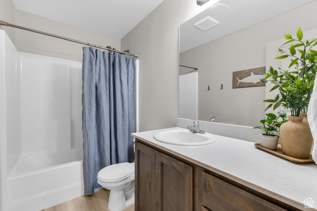 Bathroom featuring vanity, shower / bath combination with curtain, and wood finished floors