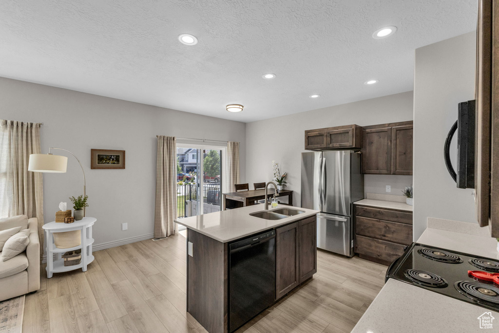 Kitchen with dishwasher, freestanding refrigerator, dark brown cabinetry, light countertops, and recessed lighting