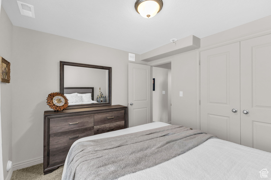 Bedroom with light colored carpet and a closet