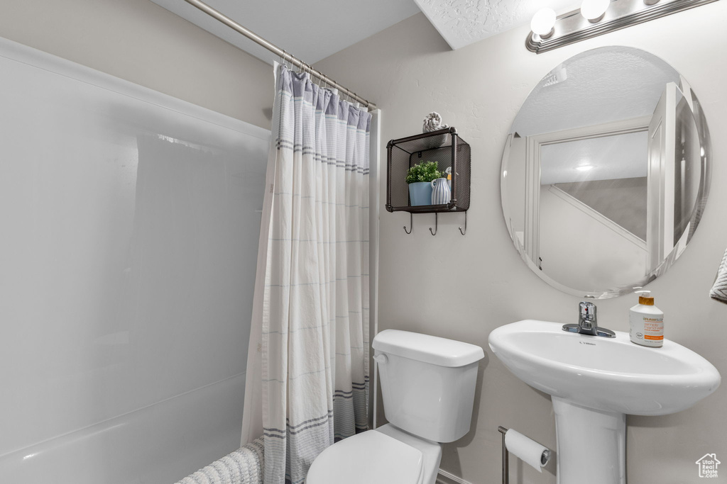 Full bathroom with toilet and shower / bath combination with curtain