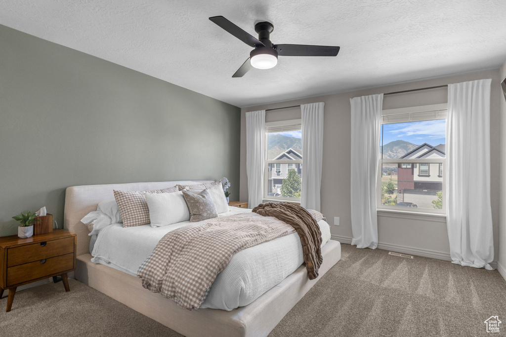Bedroom featuring carpet flooring, a textured ceiling, and a ceiling fan