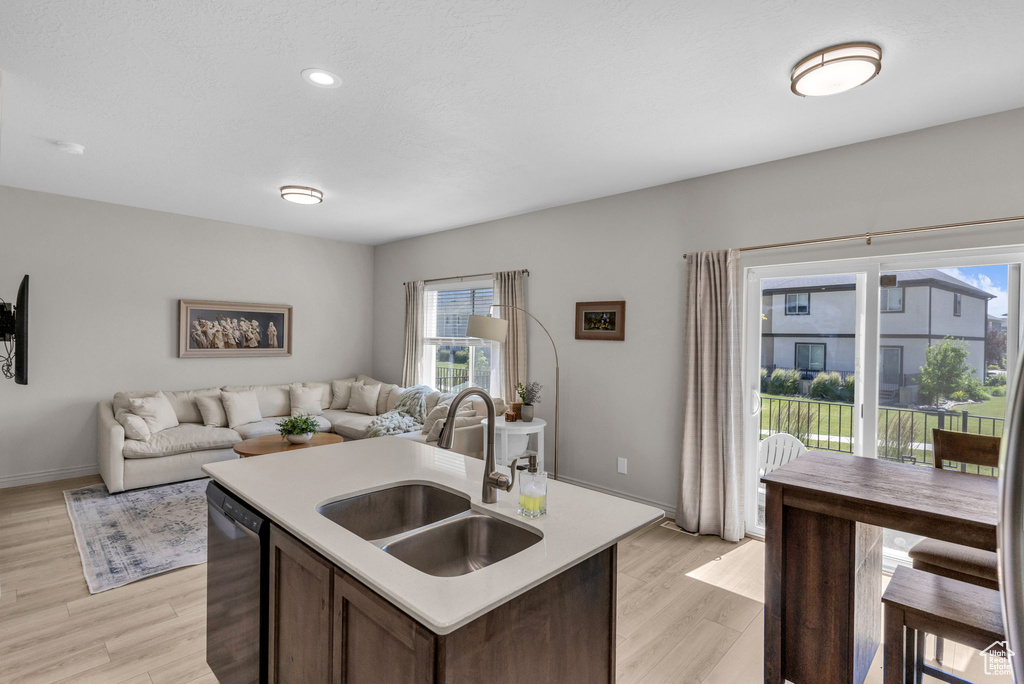 Kitchen with black dishwasher, light countertops, open floor plan, light wood-style floors, and recessed lighting