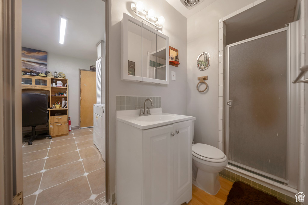 Full bathroom featuring a stall shower, vanity, tile patterned floors, and backsplash
