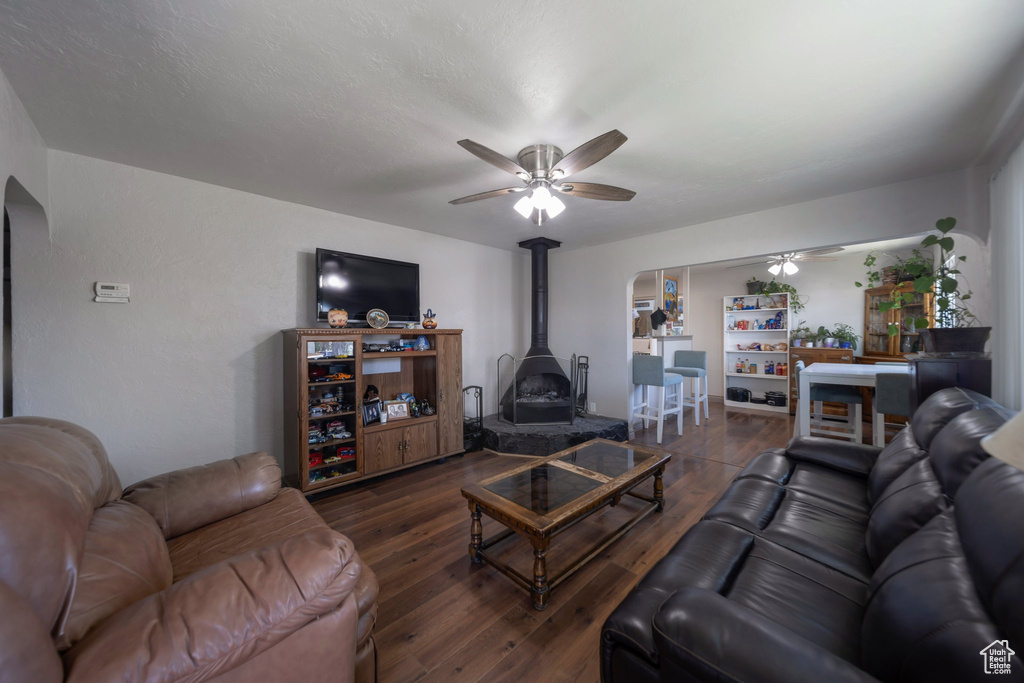 Living room featuring a wood stove, a ceiling fan, hardwood / wood-style floors, and arched walkways