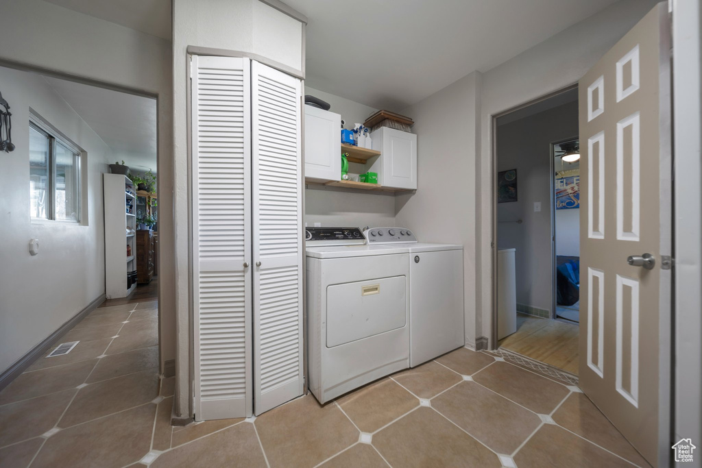 Laundry room with cabinet space, washing machine and dryer, and light tile patterned floors