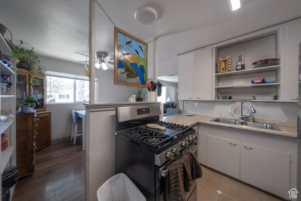 Kitchen featuring stainless steel gas range, light countertops, a ceiling fan, and white cabinetry