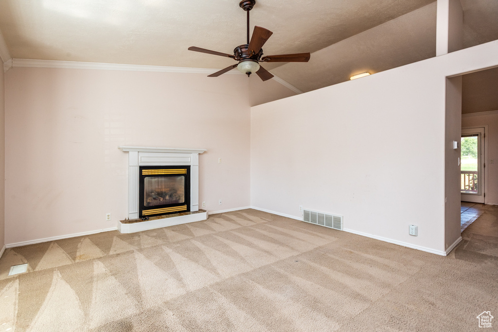 Unfurnished living room with carpet, a glass covered fireplace, ceiling fan, crown molding, and a high ceiling