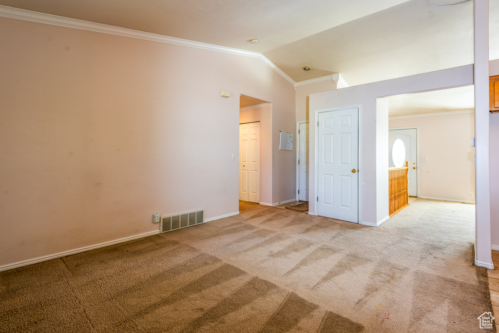 Unfurnished bedroom featuring crown molding, vaulted ceiling, and light colored carpet