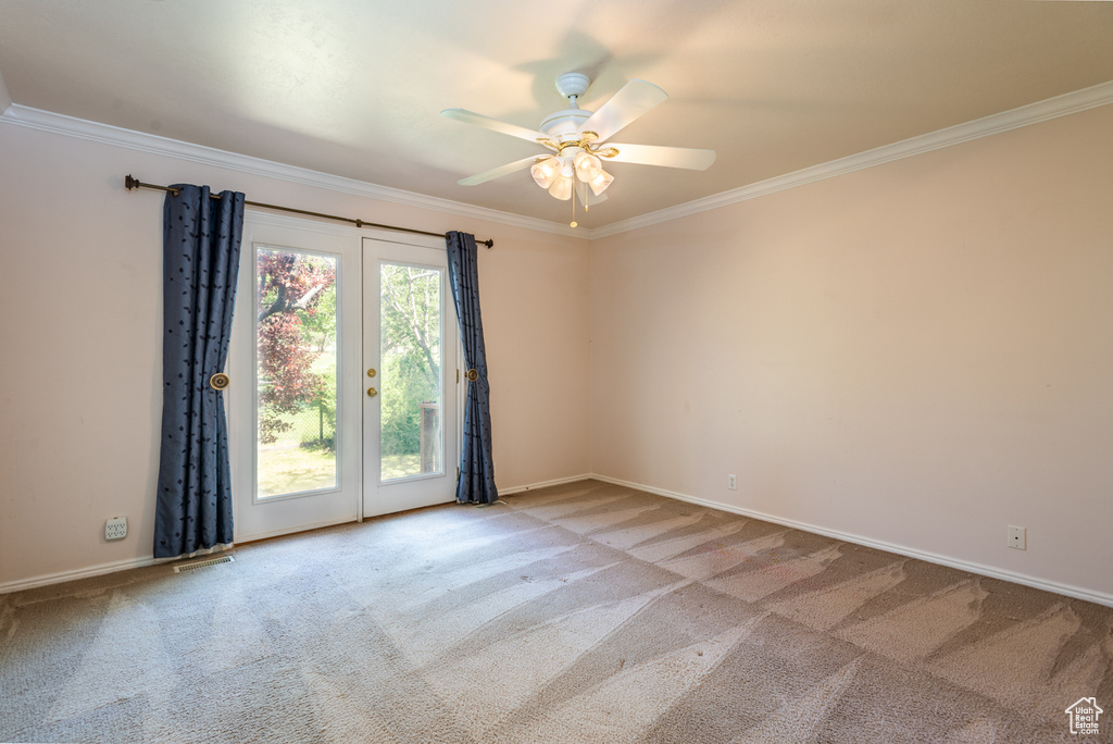 Empty room with crown molding, carpet floors, ceiling fan, and french doors