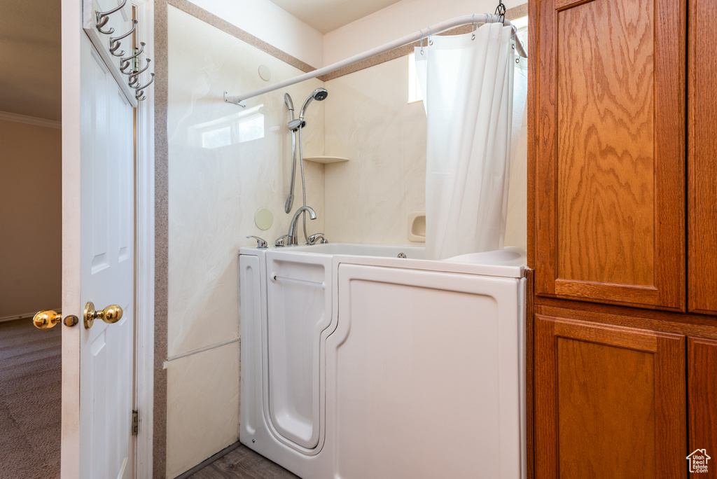 Bathroom featuring washer / clothes dryer, shower / bath combination with curtain, and ornamental molding