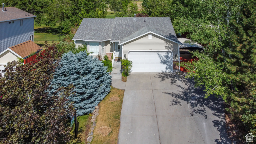 View of front facade with a garage, concrete driveway, and roof with shingles