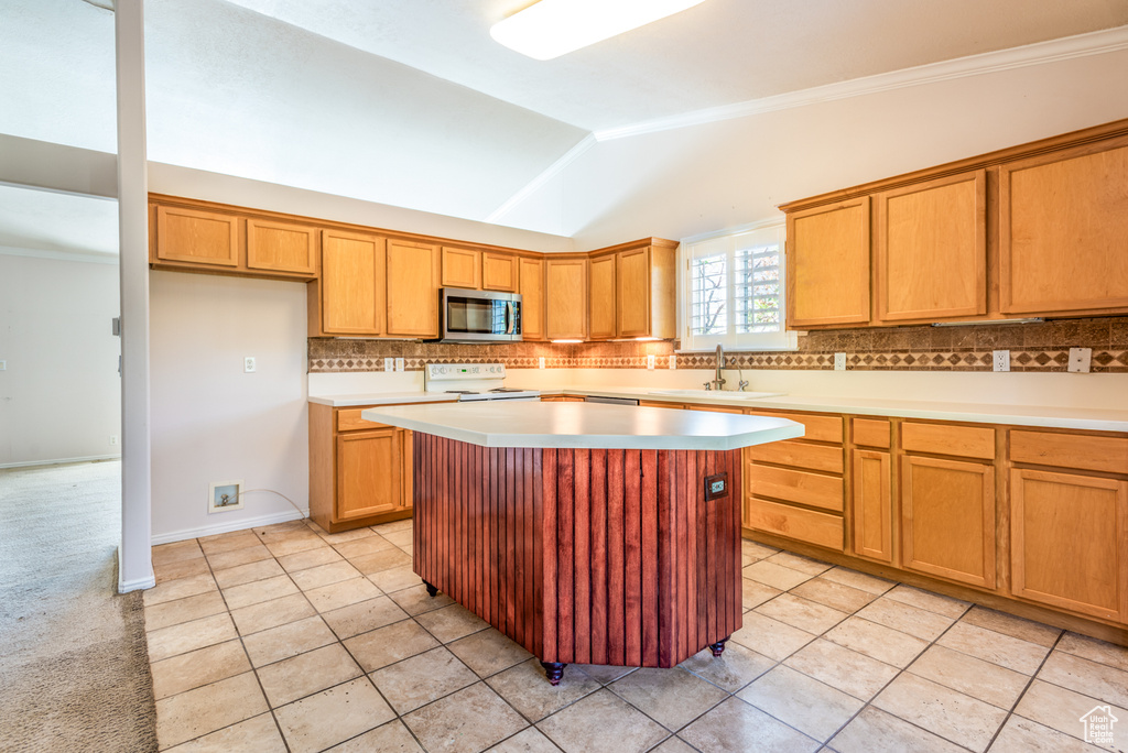 Kitchen featuring stainless steel microwave, electric stove, tasteful backsplash, vaulted ceiling, and a kitchen island